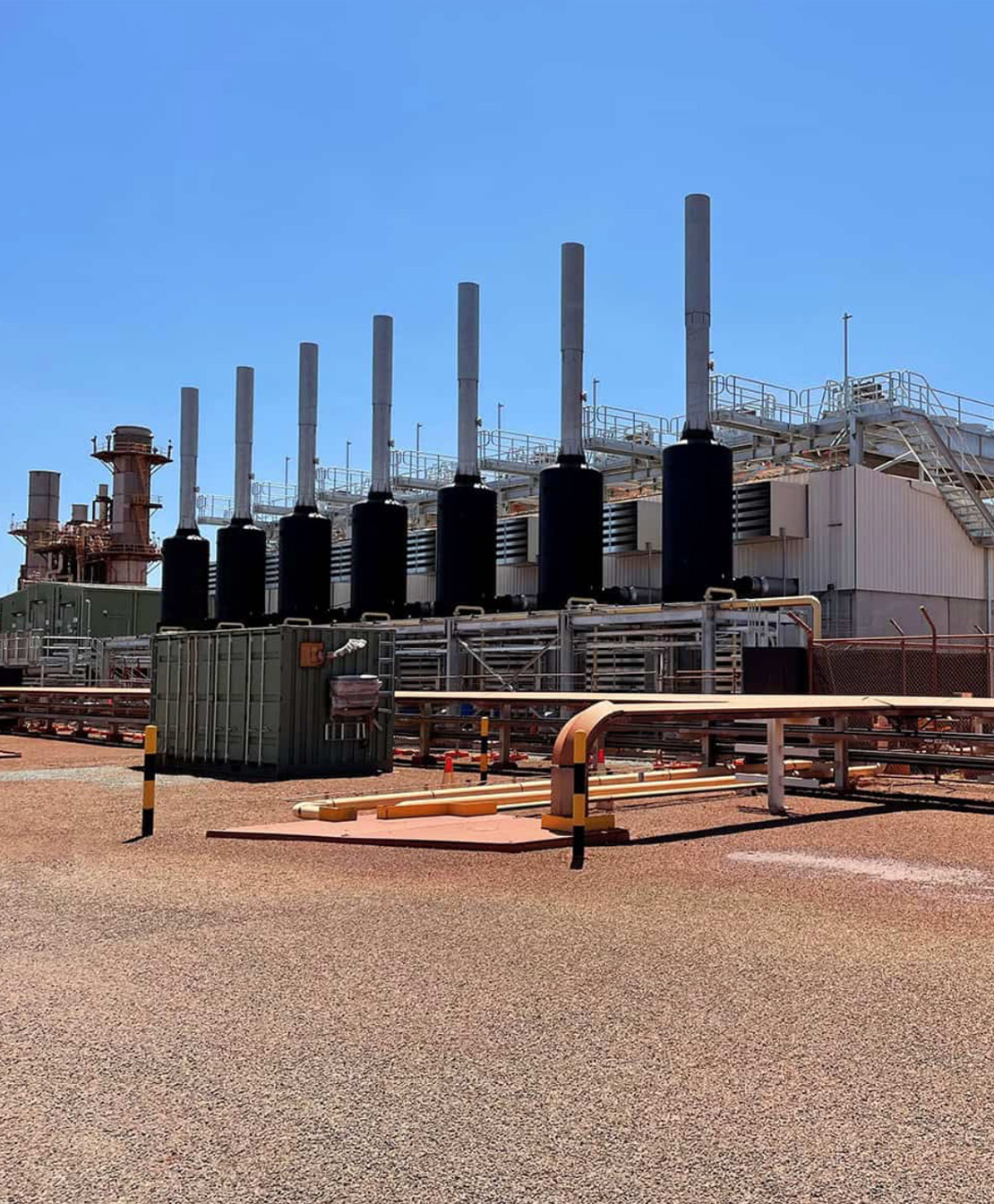 Bank of black exhaust stacks at a remote industrial power station